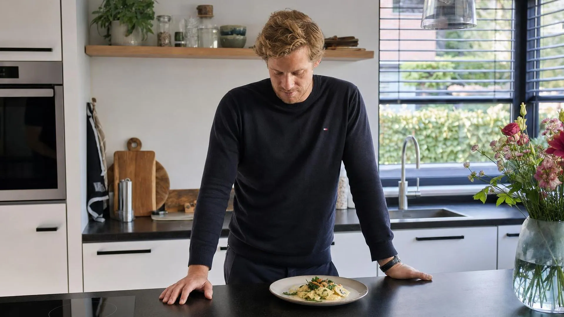 Persoon staat bij het aanrecht en kijkt naar een onaangeroerd bord eten