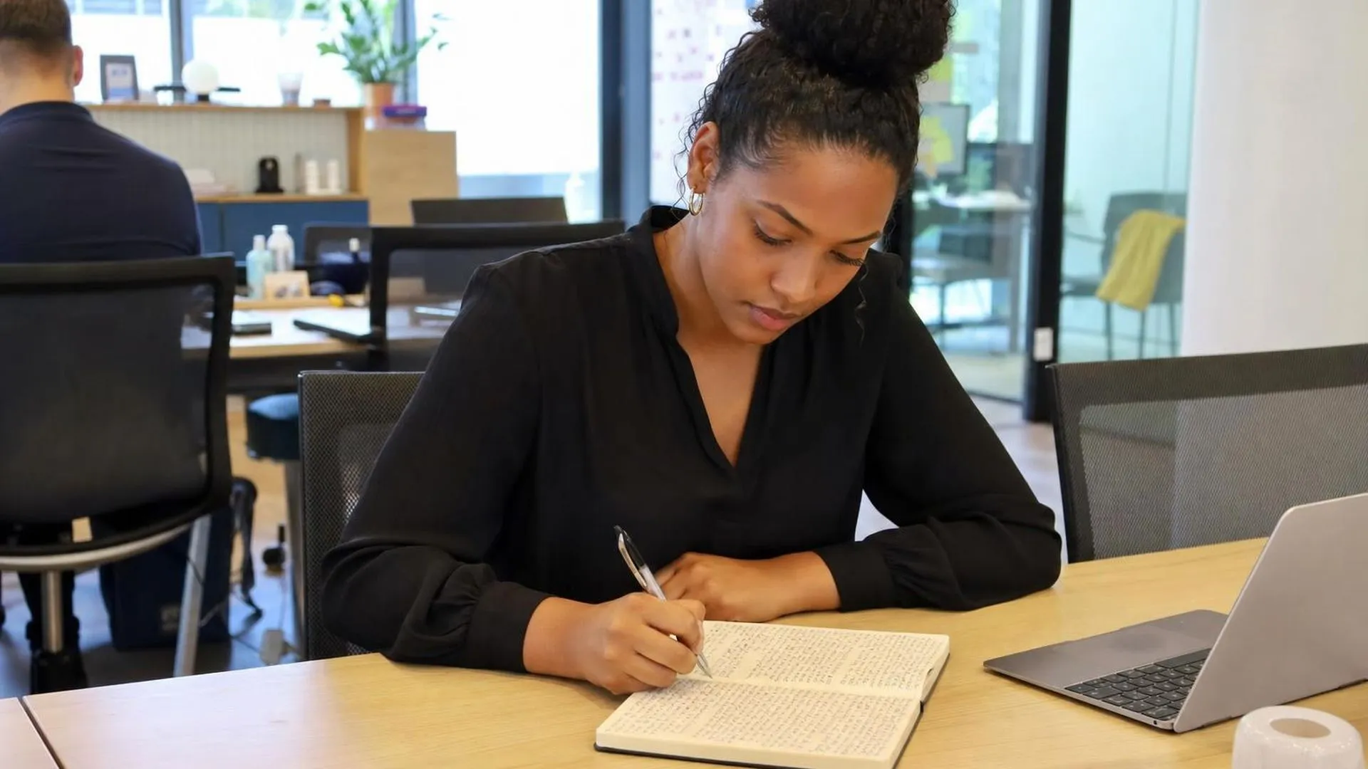 Medewerker kijkt gespannen naar een vol notitieboek op kantoor