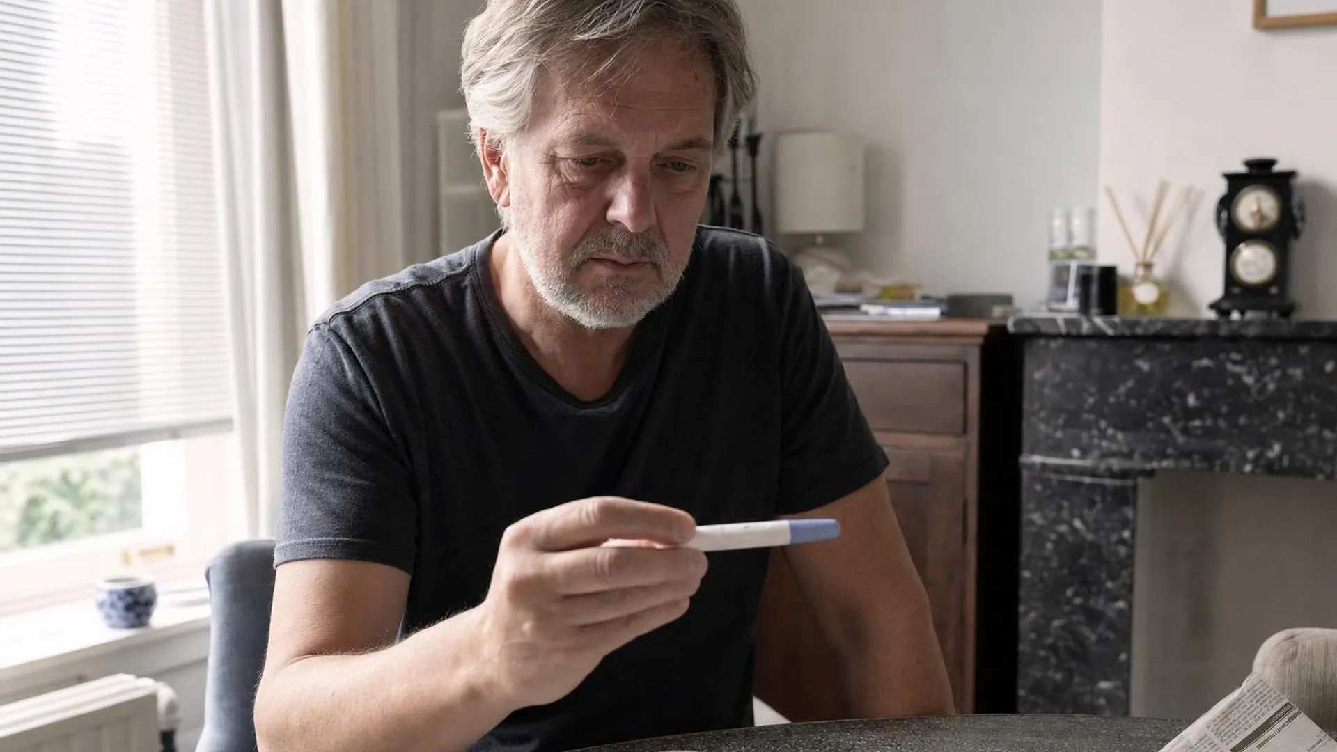 Vrouw zit aan een eettafel en kijkt naar een zwangerschapstest