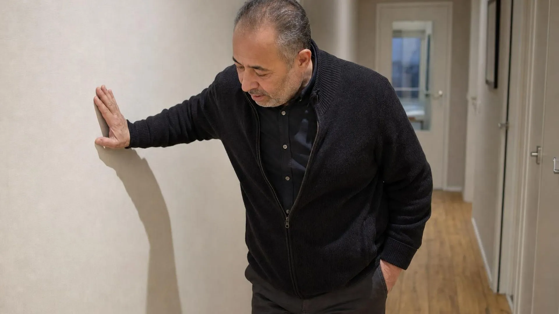 Persoon die even steunt tegen een muur, zichtbaar moe en uitgeput