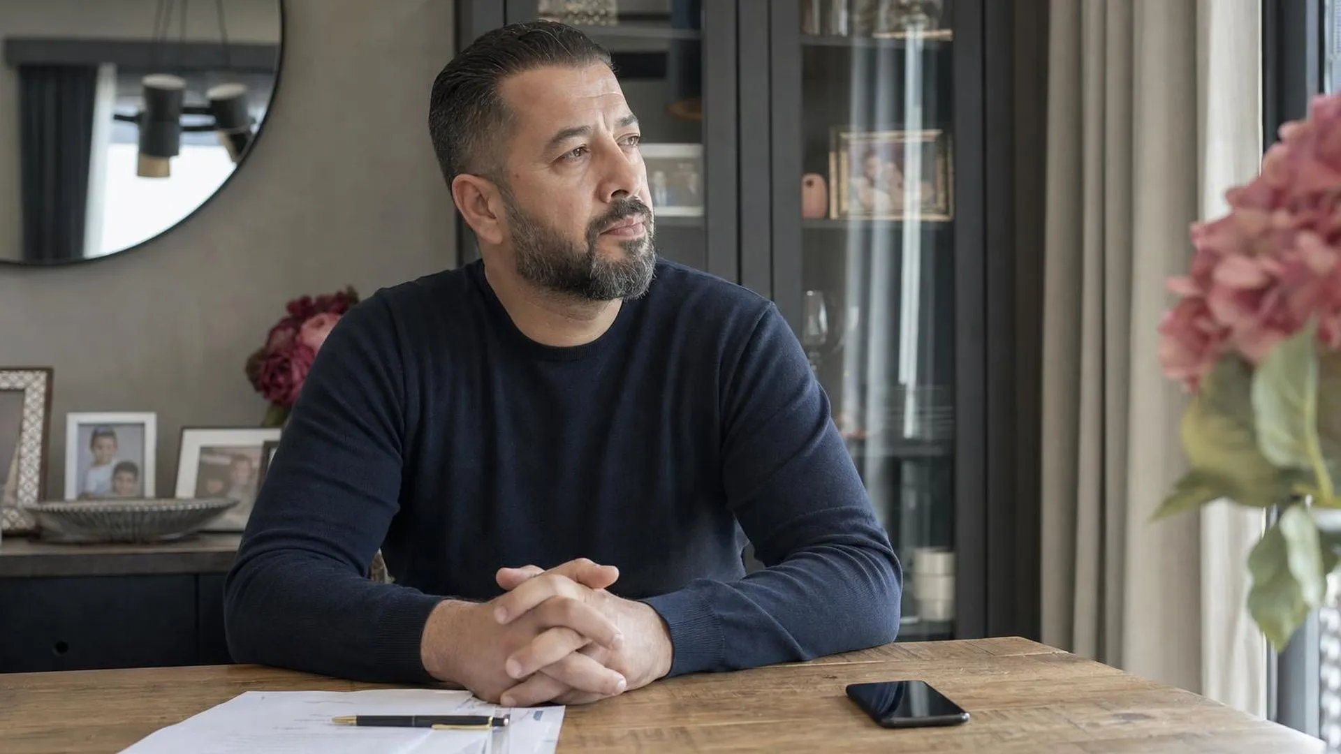 Werknemer aan tafel met papieren, kijkt afwezig voor zich uit