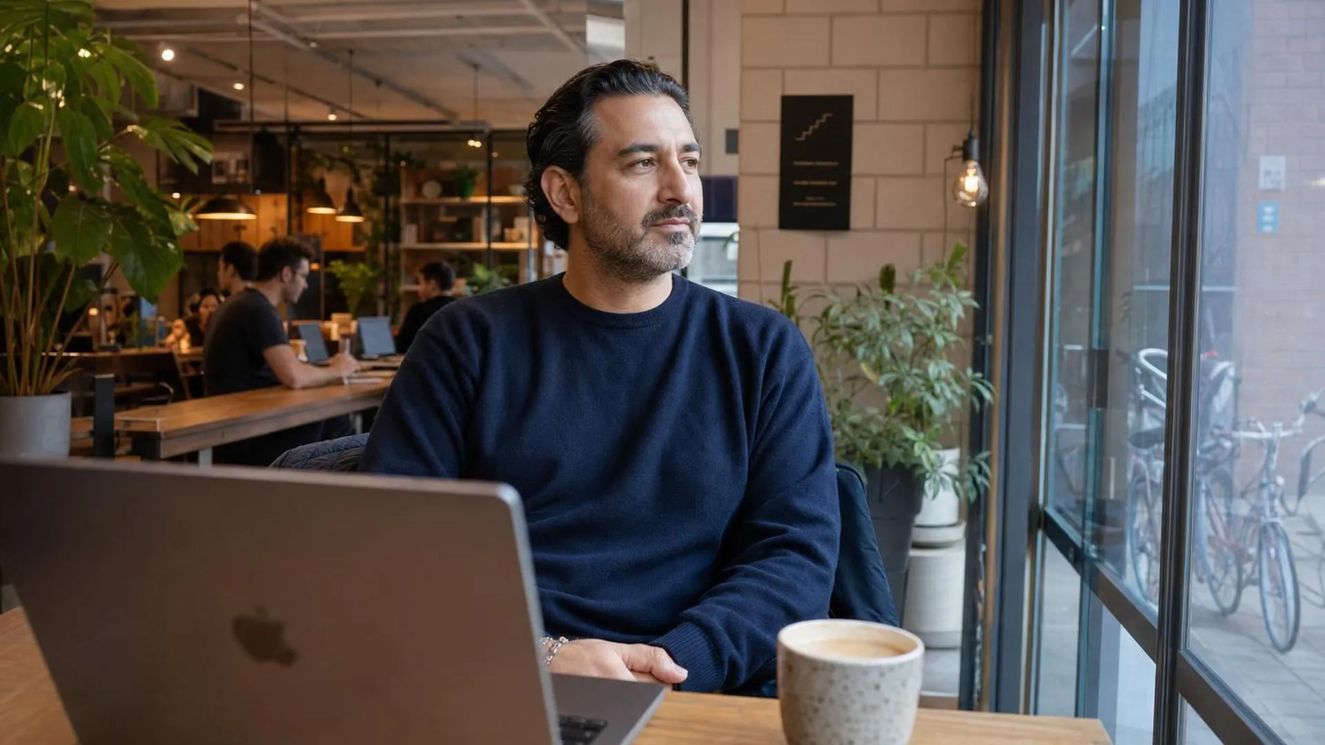 Persoon zit ongemotiveerd achter laptop in café