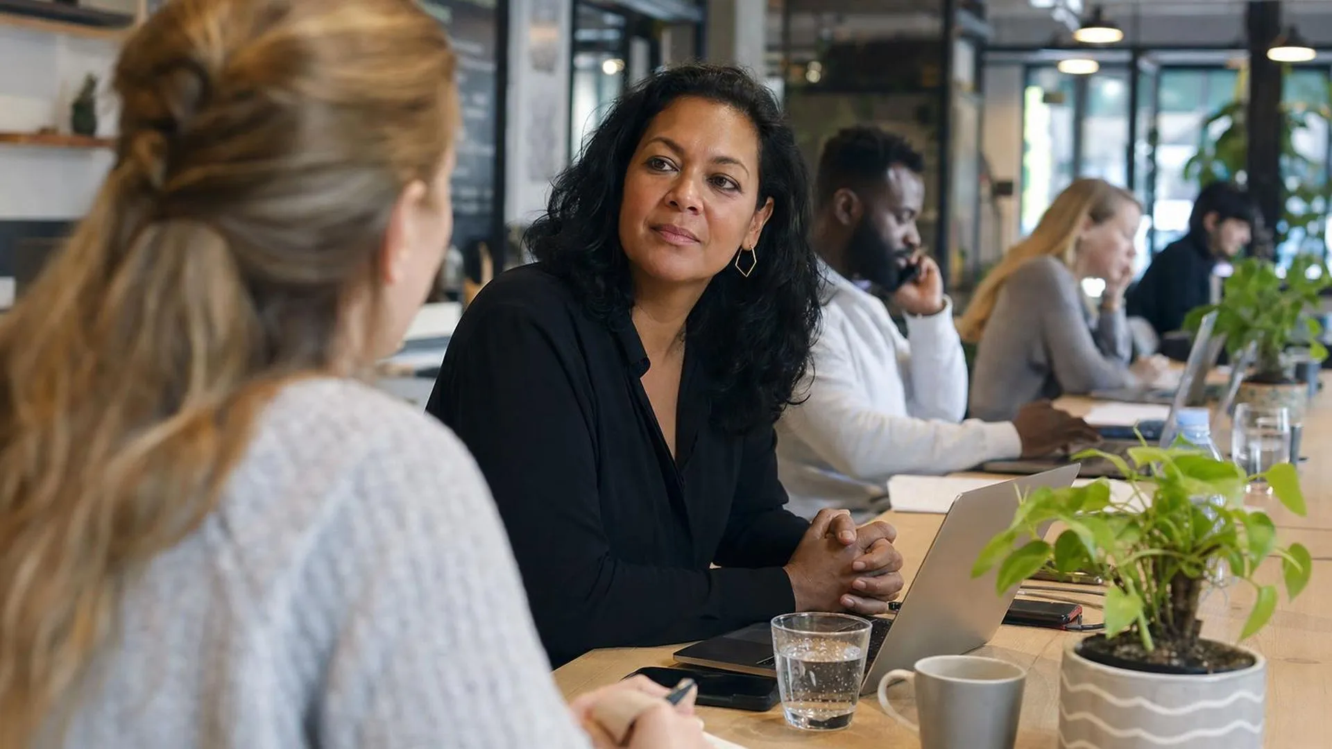 Twee collega's van verschillende leeftijden in gesprek aan een werktafel