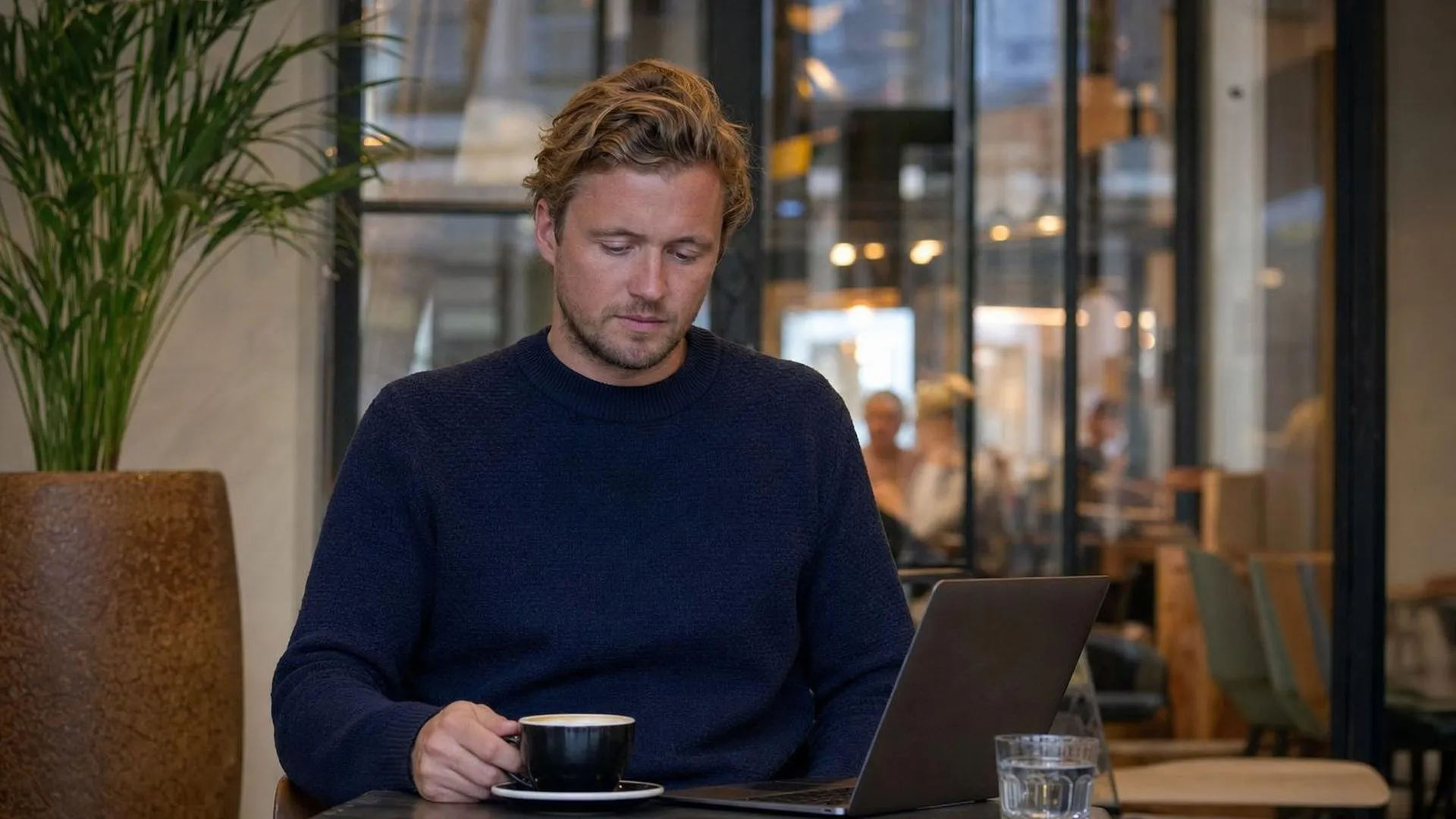Persoon die in gedachten verzonken zit in een café, alsof er iets knaagt vanbinnen