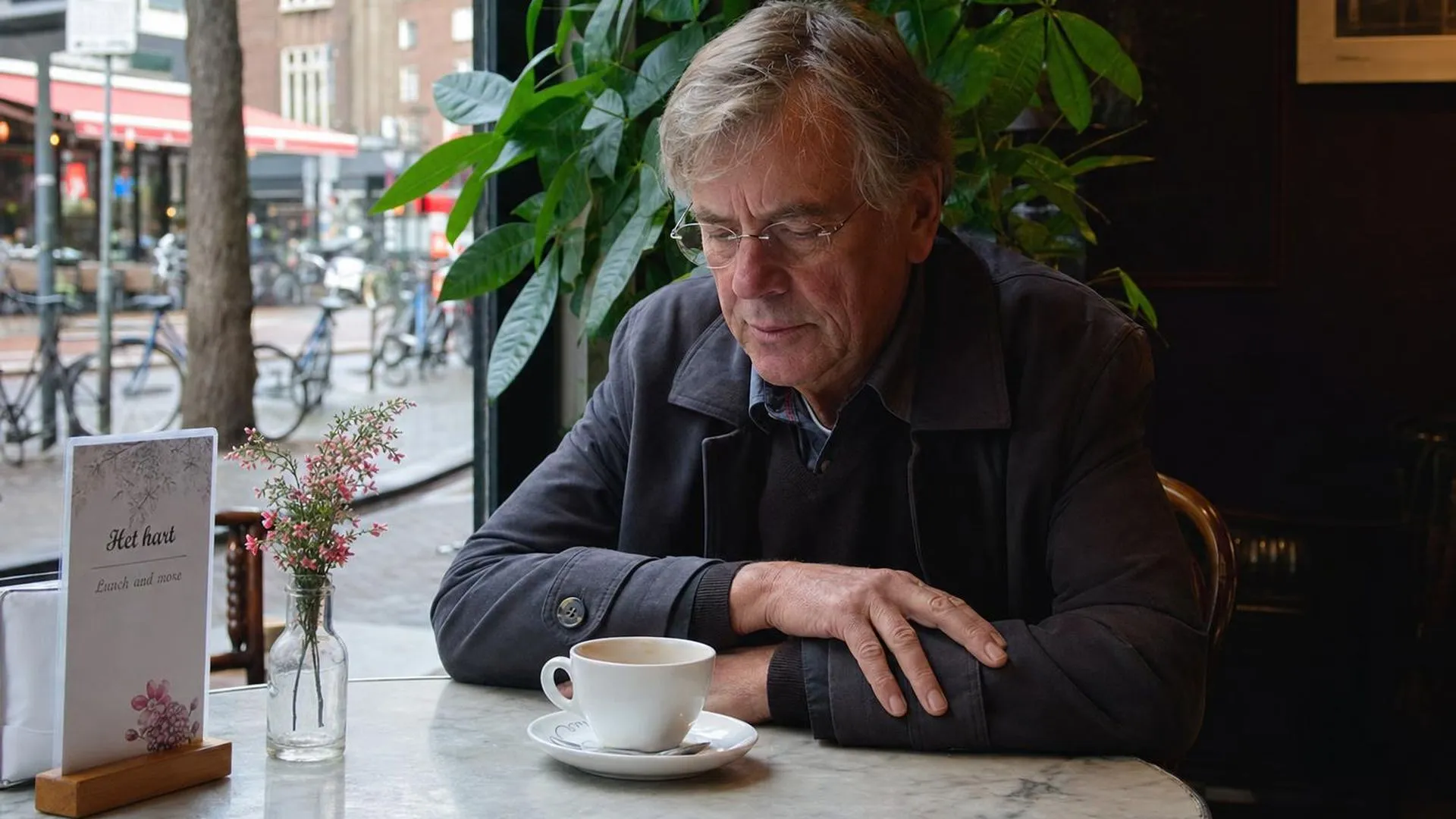 Persoon zit alleen aan een tafeltje in een café en kijkt voor zich uit