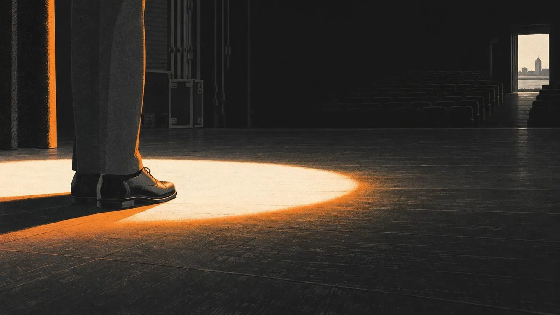 Een paar schoenen op de rand van een lichtcirkel op een verder donker, leeg toneel.