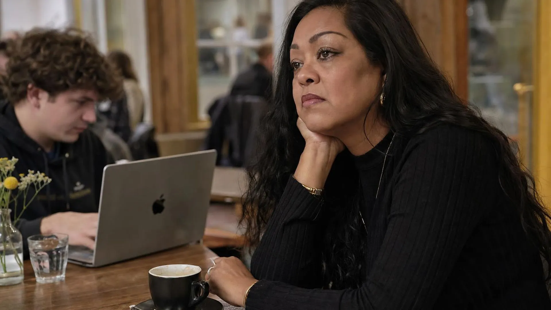 Iemand zit alleen aan een tafel in een café, in gedachten verzonken