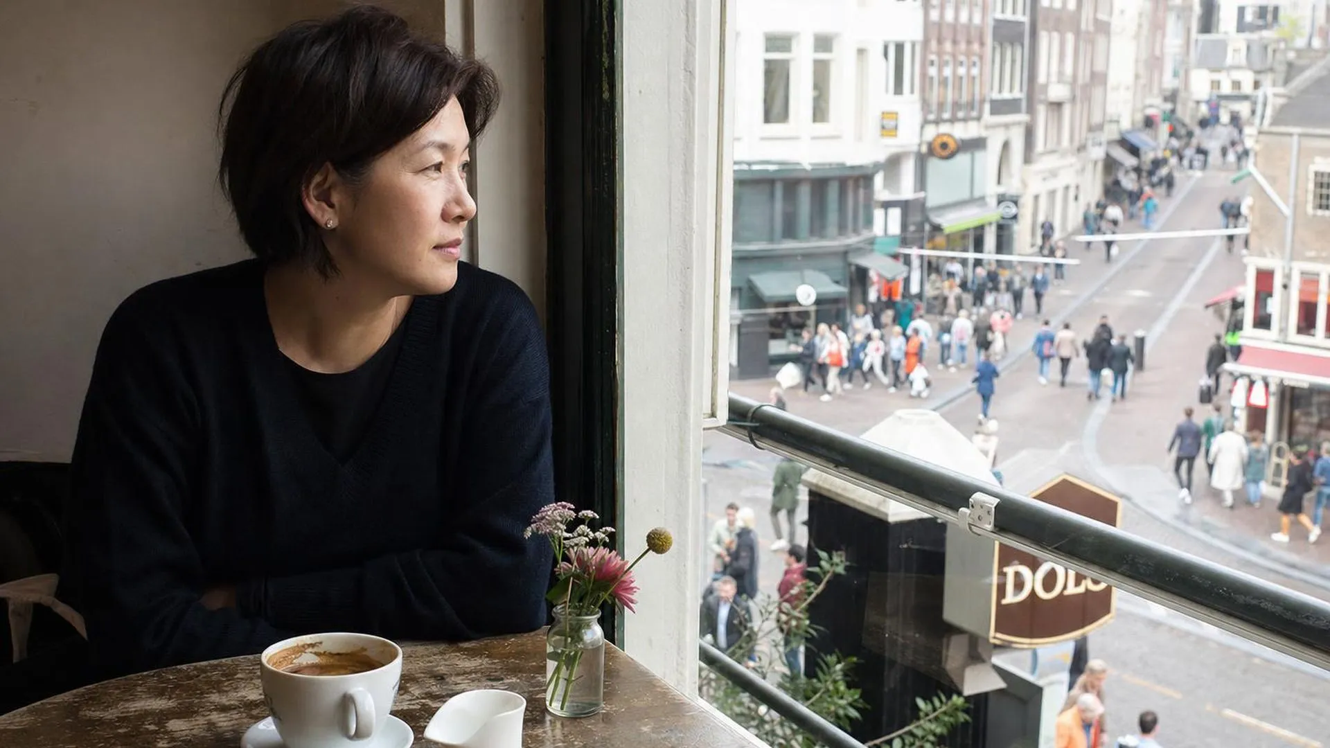 Introvert persoon zit rustig alleen aan een tafeltje en kijkt naar buiten