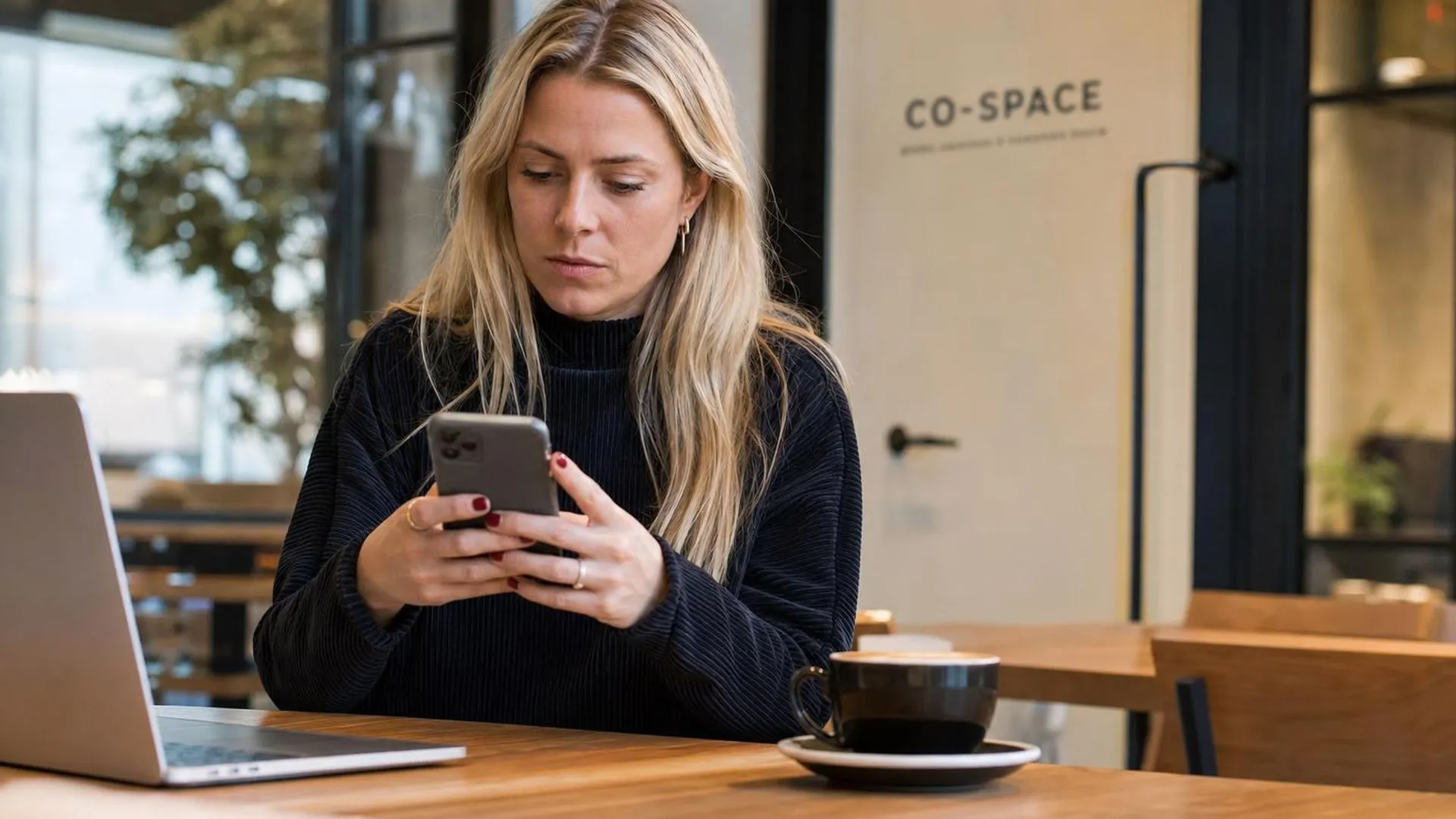 Persoon staart naar telefoon in café, zichtbaar gespannen