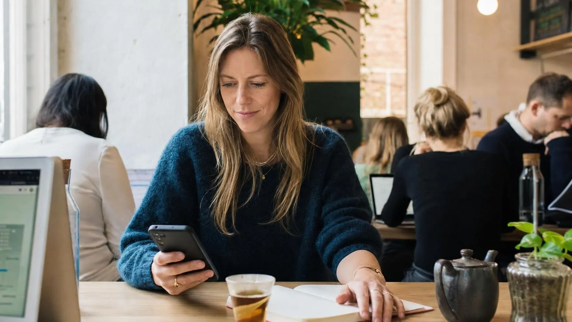 Persoon die zichzelf wegcijfert aan een tafeltje in een café