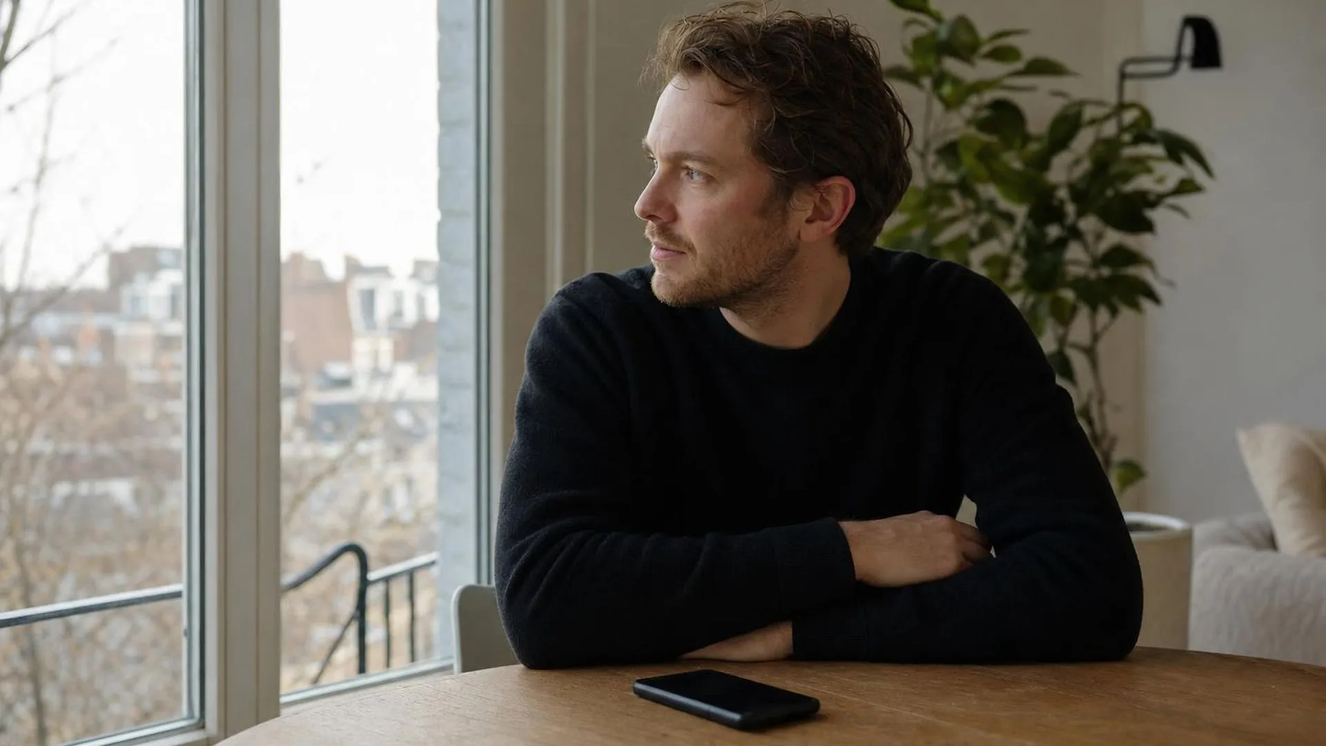 Persoon thuis tijdens ziekte, kijkend naar buiten aan de eettafel