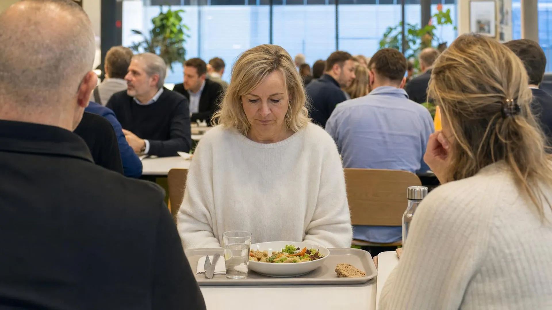 Medewerker met faalangst zit afwezig aan tafel tijdens lunchpauze op kantoor