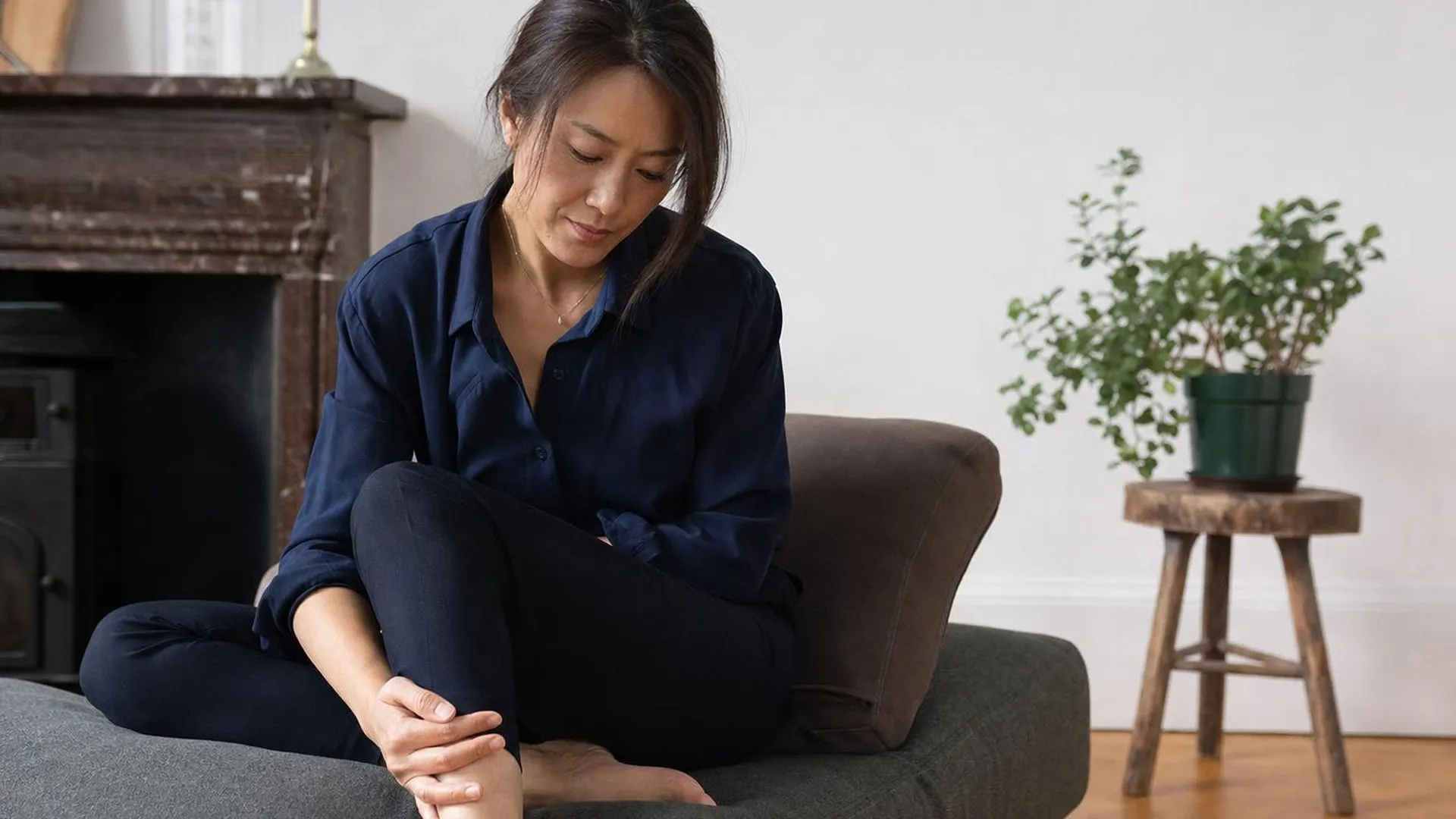 Persoon met neuropathische pijn zit rustig op de bank en houdt een hand bij het been