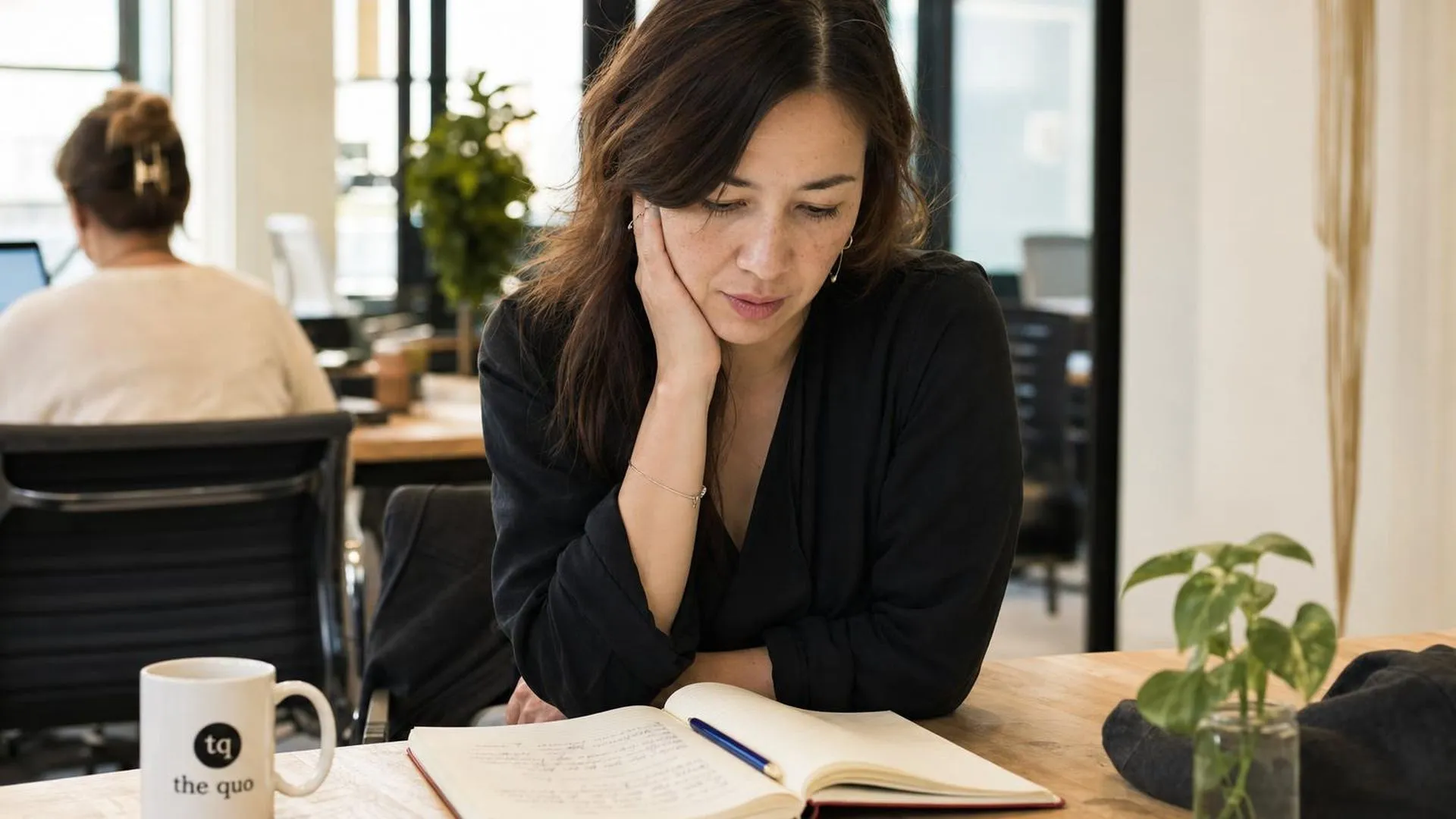 Persoon met hand tegen de kaak aan een werktafel, zichtbaar ongemak