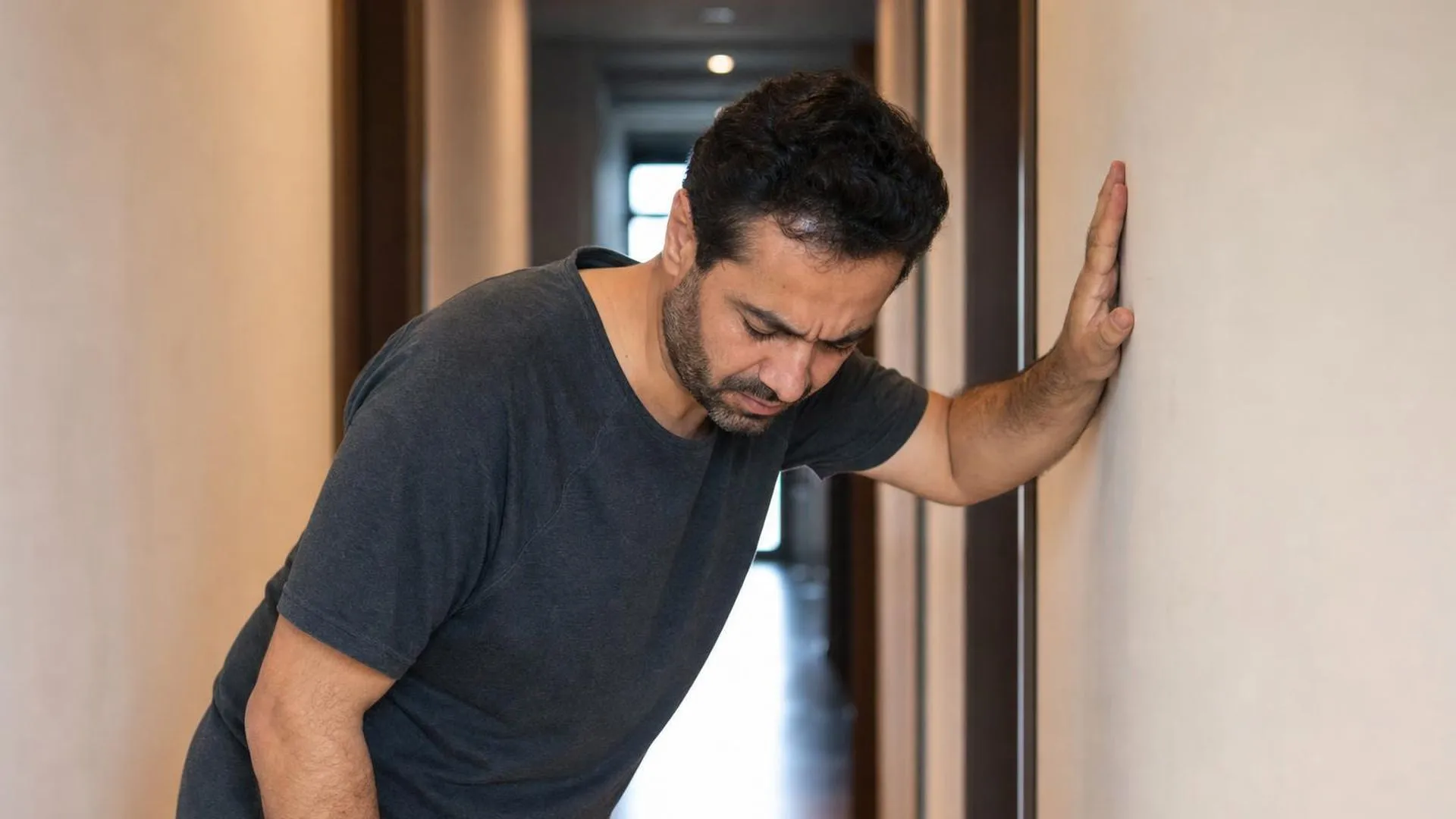 Persoon die zich vasthoudt aan een muur, moe en stijf na het opstaan