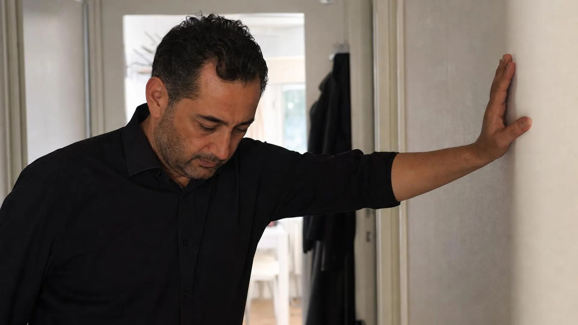 Persoon die even pauzeert in een gang, hand tegen de muur