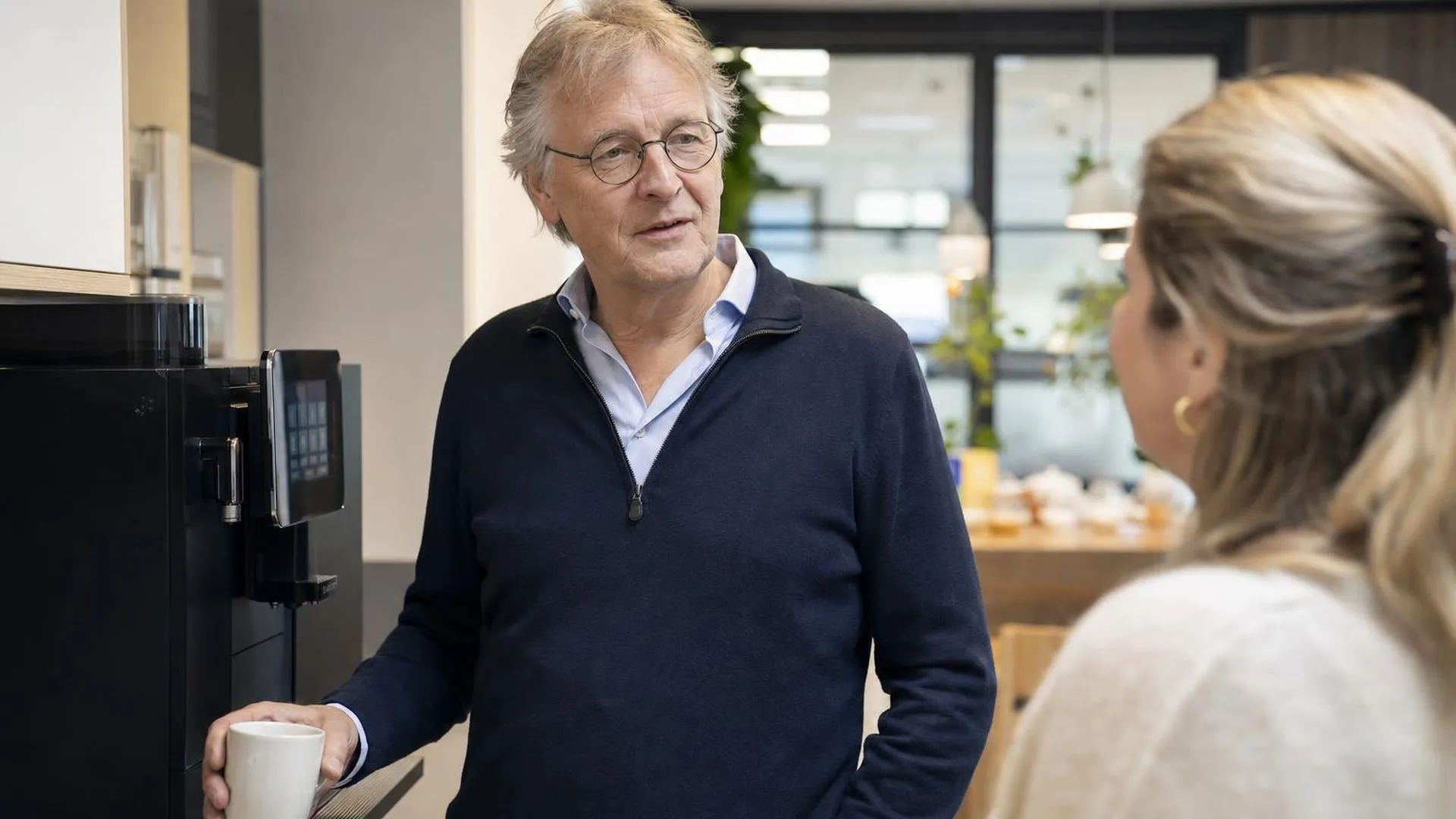 Twee collega's in gesprek bij de koffieautomaat op kantoor
