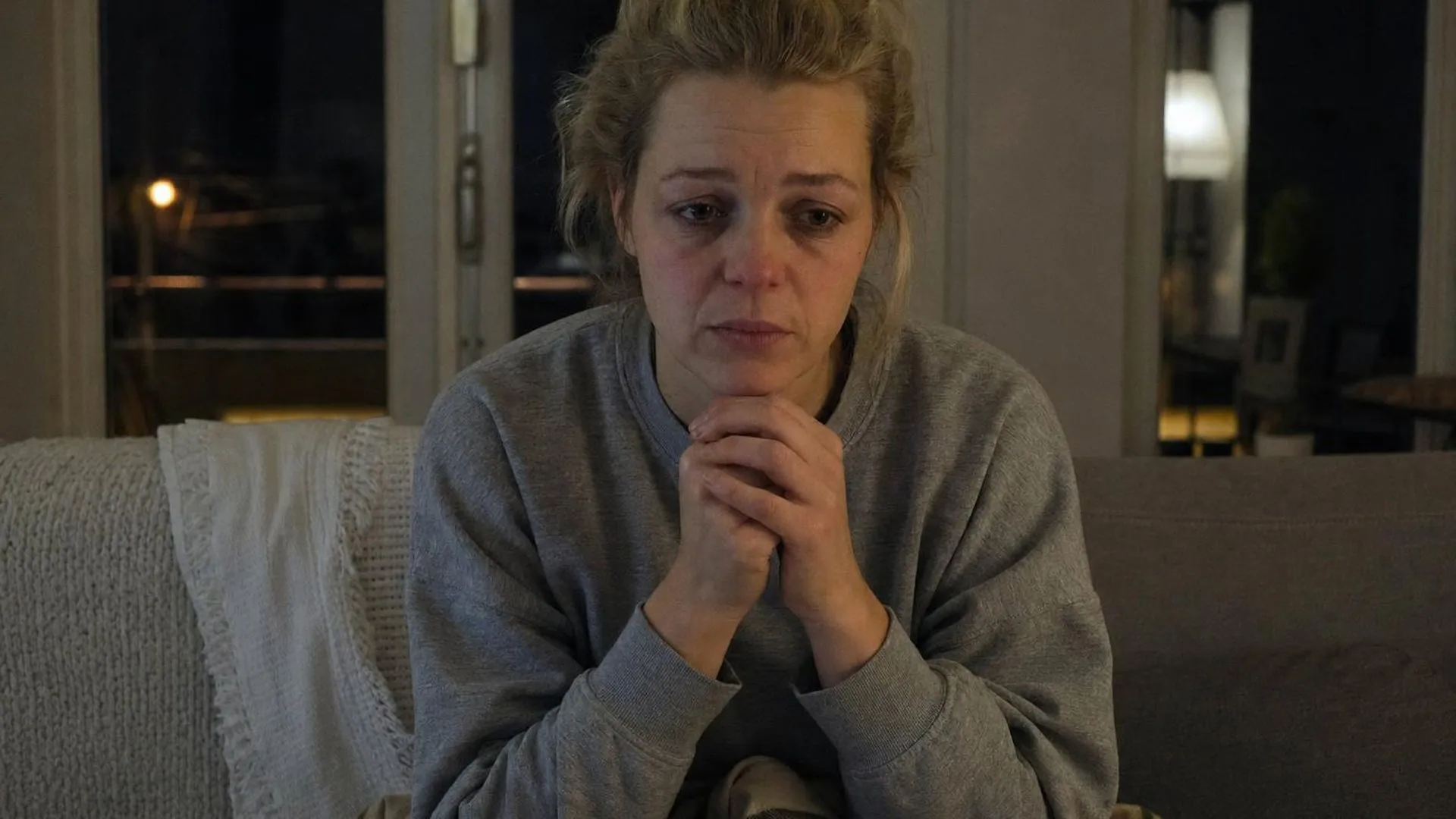 Vrouw met tintelende handen op de bank, vermoeid en bezorgd