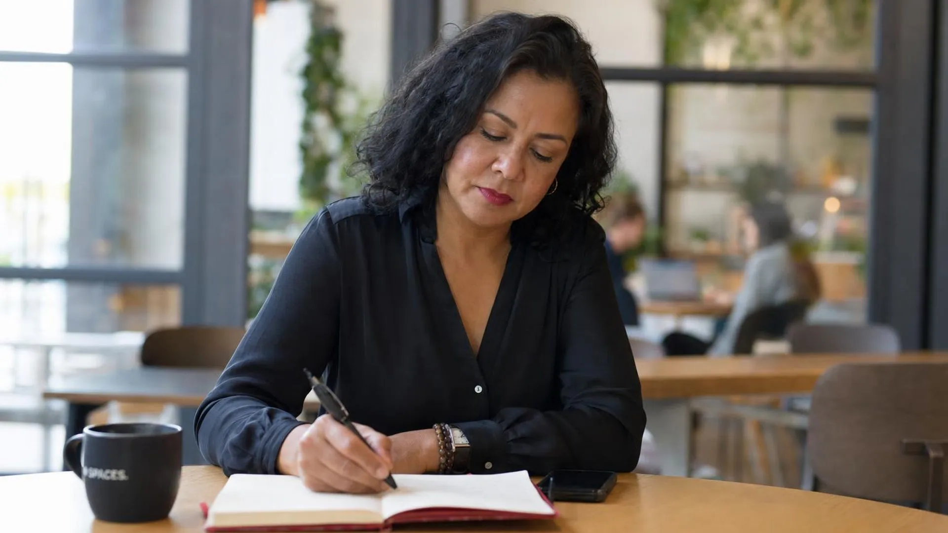 Persoon schrijft doelen op in notitieboek aan een cafétafel