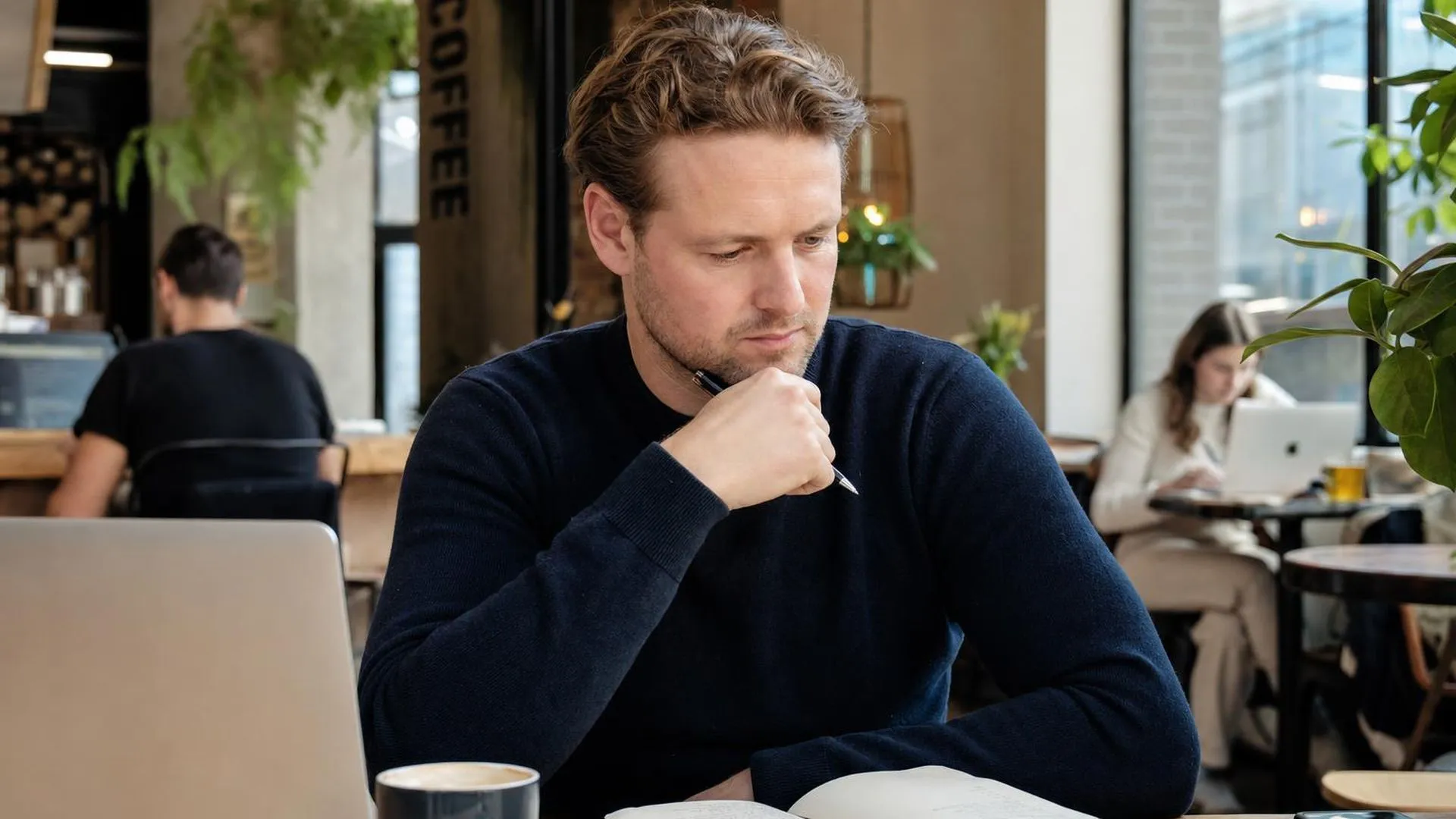Persoon die peinzend naar een notitieboek kijkt in een rustig café
