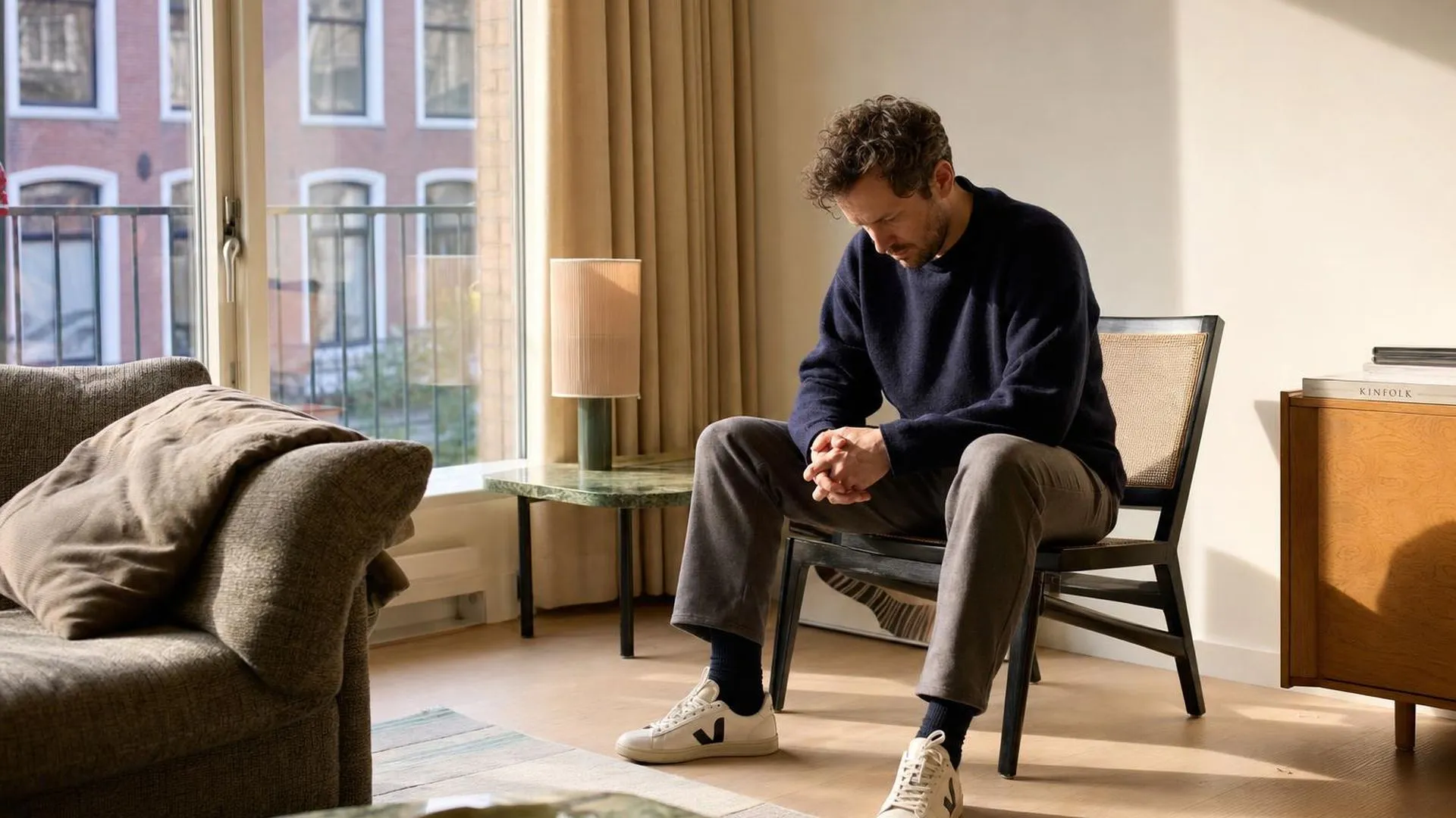 Persoon zit stil en in gedachten verzonken in een woonkamer