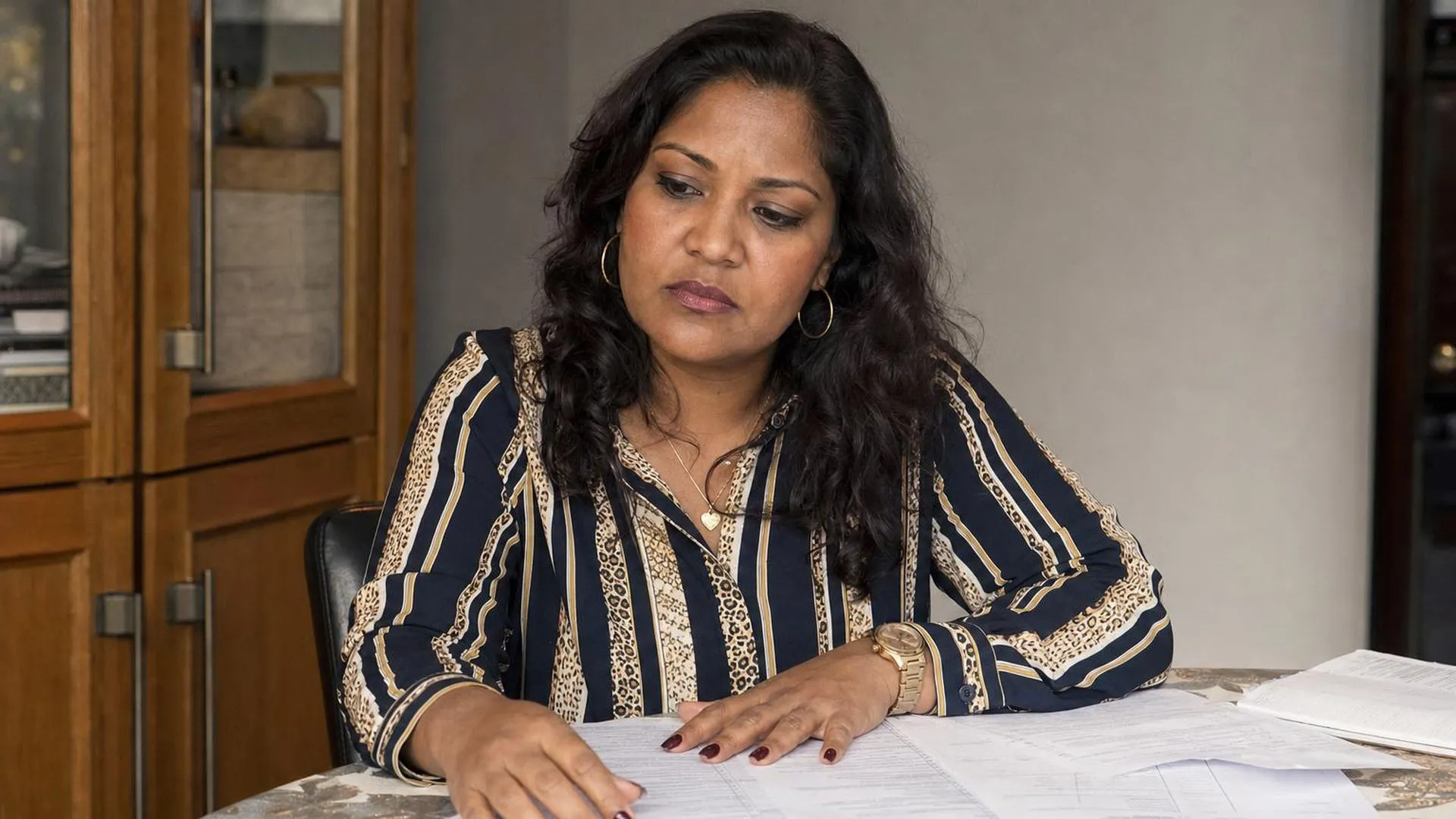 Persoon aan tafel met documenten, nadenken over een beslissing