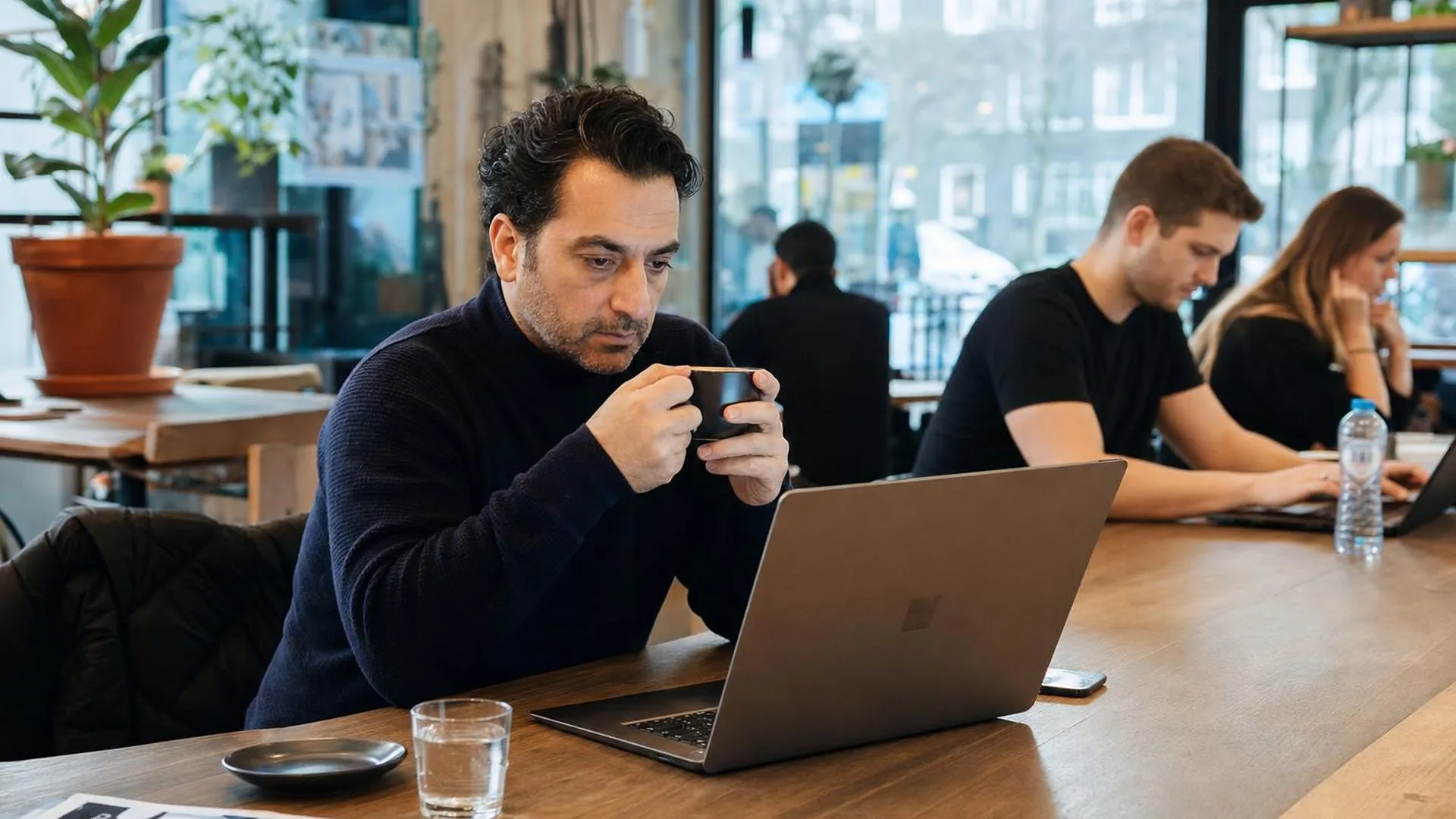Persoon staart peinzend naar laptop in een café, symboliseert vastlopen in je werk