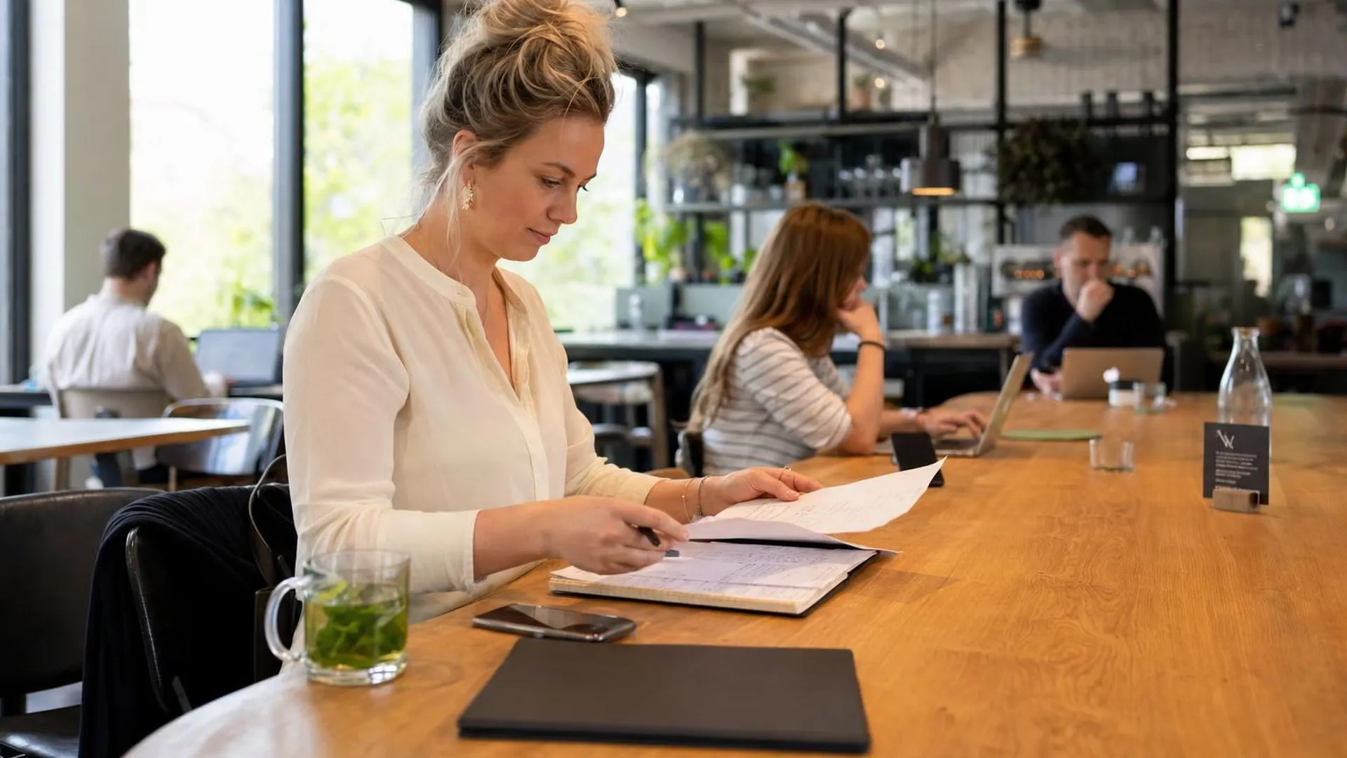 Medewerker werkt ontspannen aan een gedeelde werktafel
